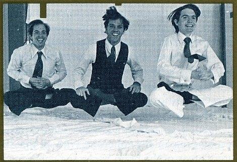 Three men jumping indoors, smiling widely.